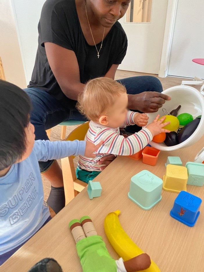 Assistante maternelle aidant des enfants à explorer des fruits jouets